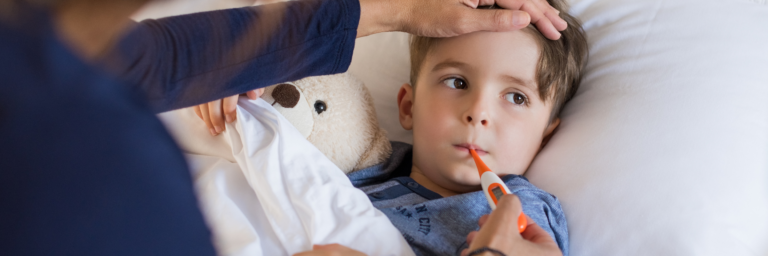 a child lying in bed with a thermometer