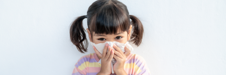 a girl with pigtails blowing her nose in a tissue
